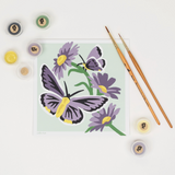 Painting of butterflies and flowers with painting supplies on a white background