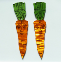 Carrot-shaped earrings with face designs on a white plate with a red checkered border.