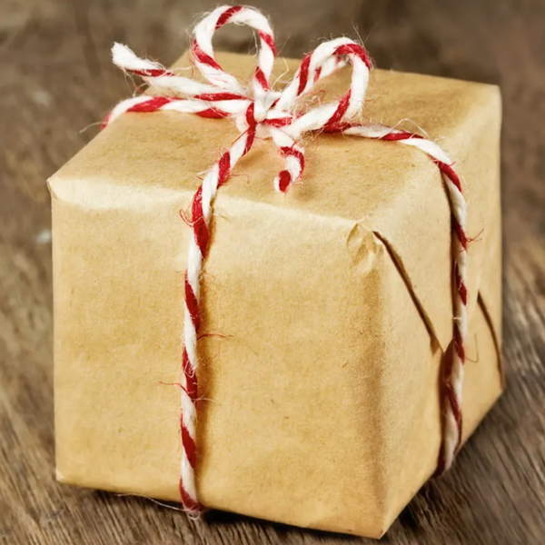 Brown paper-wrapped gift with red and white string on a wooden surface