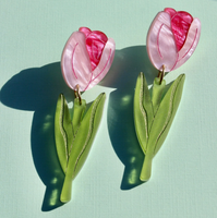 Pink tulip-shaped earrings on a light green background