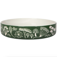 Green bowl with white floral and mushroom pattern on a white background