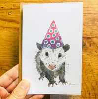 Illustration of a possum wearing a party hat on a wooden surface