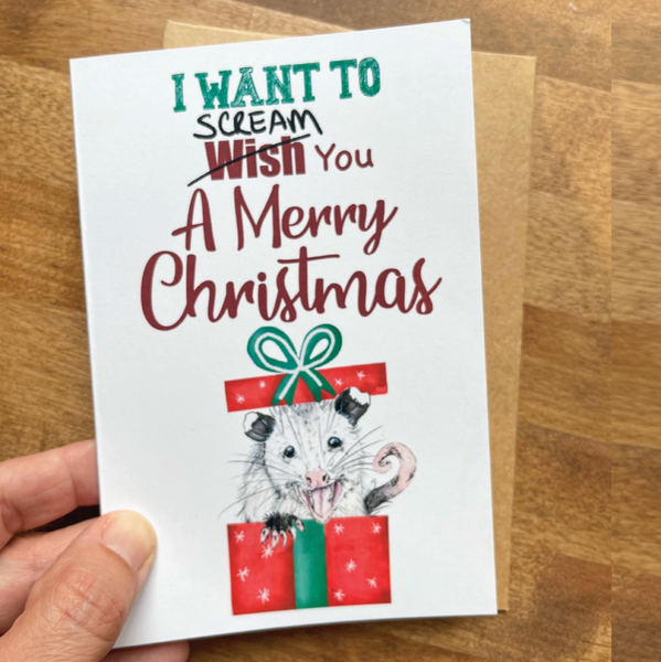 Christmas card with opossum illustration and text on a wooden surface