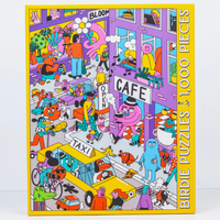 Jigsaw puzzle box with colorful illustration of a street scene, featuring a cafe and taxi.