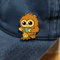 Blue cap with a cartoon-like creature holding a cup on a textured surface