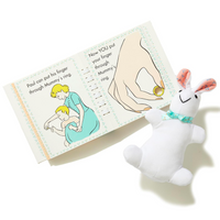 Plush toy resembling a rabbit next to a children's book on a white background
