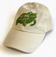 Beige cap with green frog graphic and 'Being Myself' text on a white background
