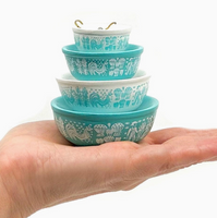 Stack of turquoise ceramic bowls held in a hand against a white background