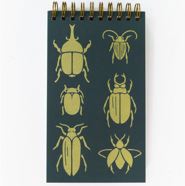 Notebook with gold beetle illustrations on a dark green background
