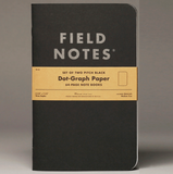 Black Field Notes notebook with a yellow label on a gray background